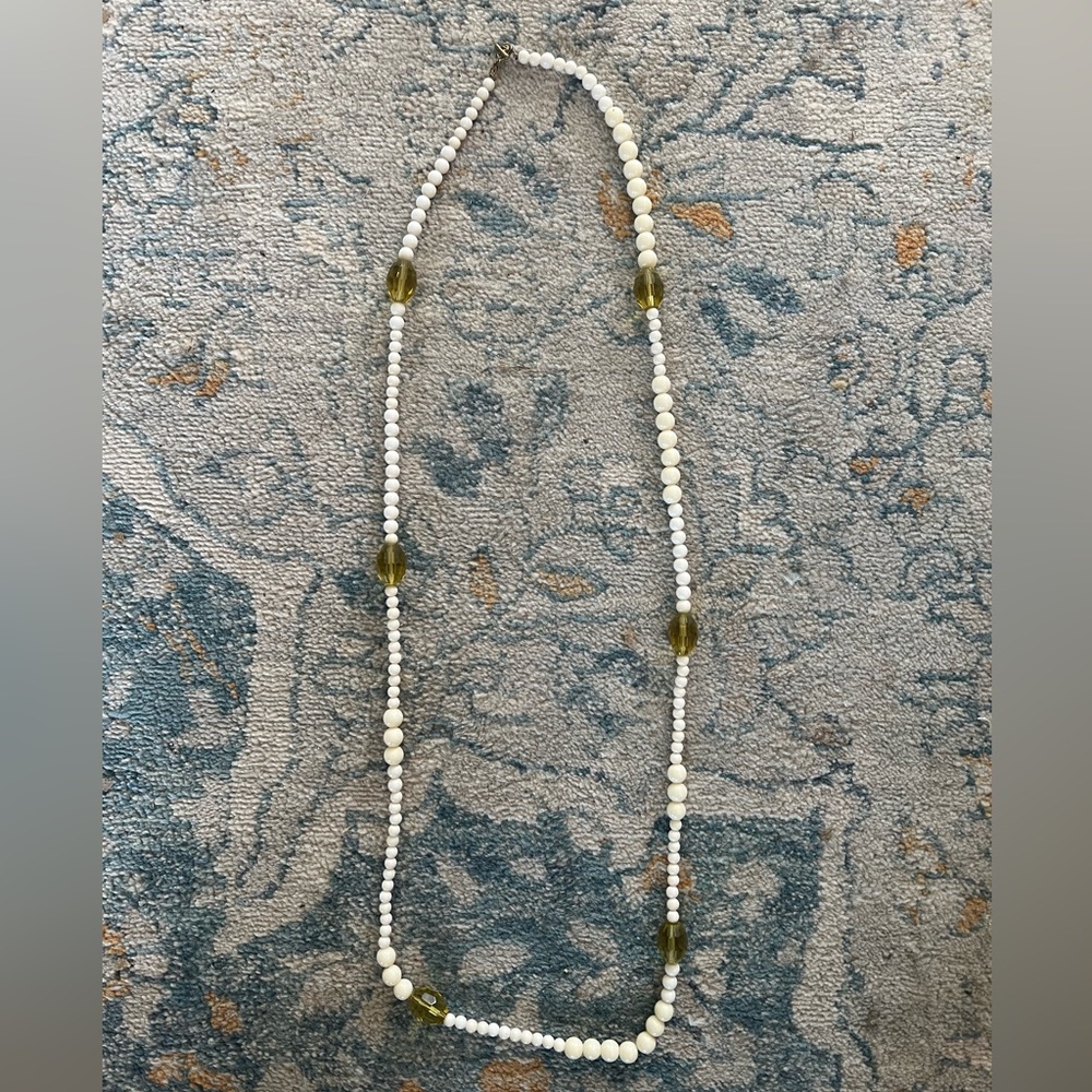 Beaded necklace. 18” long. Cream and greenish amber beads with clasp in back.